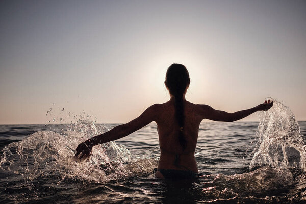 Beautiful emotional Model Girl making splash in the sea and laughing. Beautiful Woman Hot Girl enjoying the Waves of the Ocean. Tropical vacation