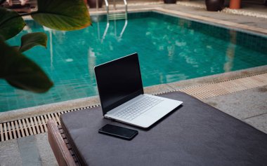 Havuzda beyaz dizüstü bilgisayar, akıllı telefon, tatilde serbest çalışan biri..