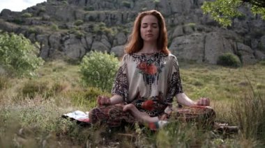 Güzel ve sağlıklı kızıl kadın usulca nefes alıyor ve nilüfer çiçeği pozisyonunda oturuyor.