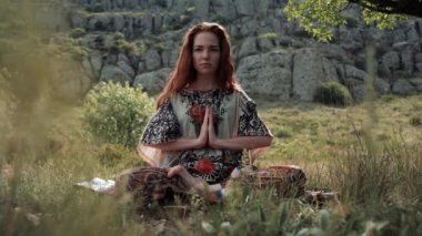 Güzel ve sağlıklı kızıl kadın usulca nefes alıyor ve nilüfer çiçeği pozisyonunda oturuyor.
