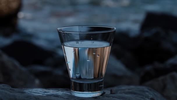 Detailní sklo s pitnou vodou stojící na pláži. — Stock video