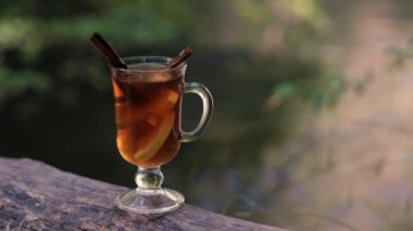 Bir bardak çay nehir kıyısındaki doğada duruyor.