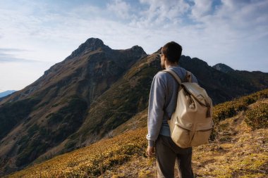 Sonbaharda dağlarda genç bir hippi. Keşif Yolculuğu Konsepti. Buzlu arka planda bir turist. Spor ve aktif yaşam konsepti.