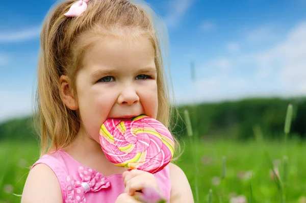 Маленькая девочка ест леденец — стоковое фото