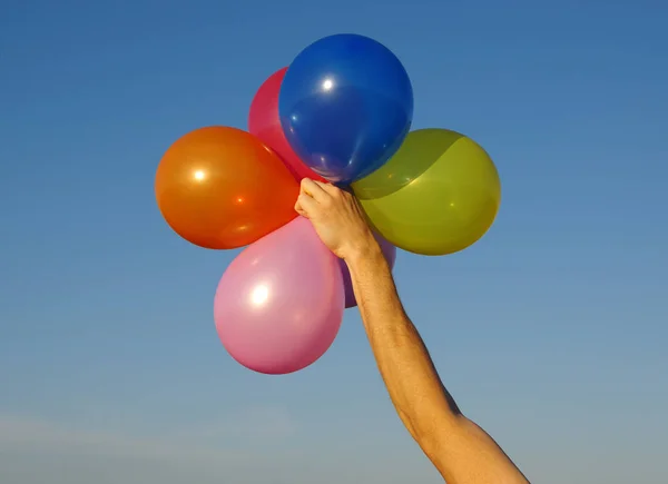 Mão segurando balões coloridos — Fotografia de Stock