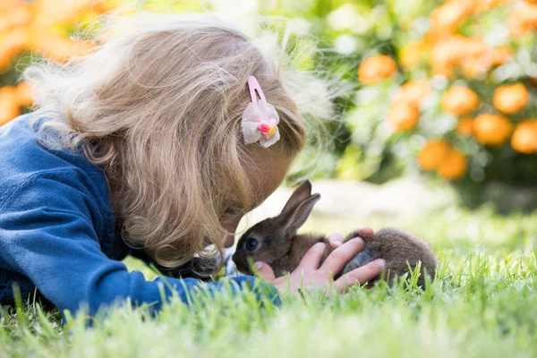 Feliz niña riendo jugando con un conejo bebé . —  Fotos de Stock