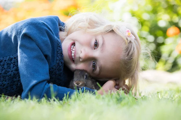 Feliz niña riendo jugando con un conejo bebé . — Foto de Stock