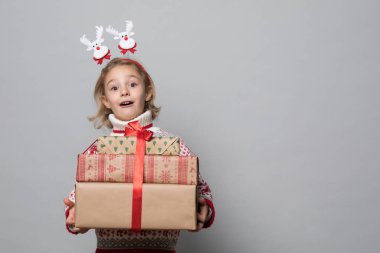 Kırmızı kazaklı, gülen çocuk elinde Noel hediyesi tutuyor..