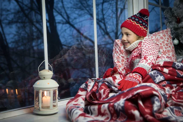 Маленькая девочка сидит у окна и рождественская елка — стоковое фото