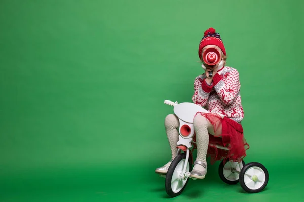 Happy little girl sitting on a small bike at Christmas time — Stock Photo, Image