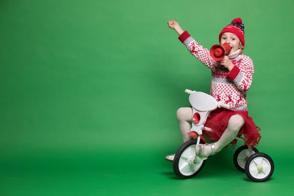 Menina feliz sentada em uma bicicleta pequena na época do Natal — Fotografia de Stock