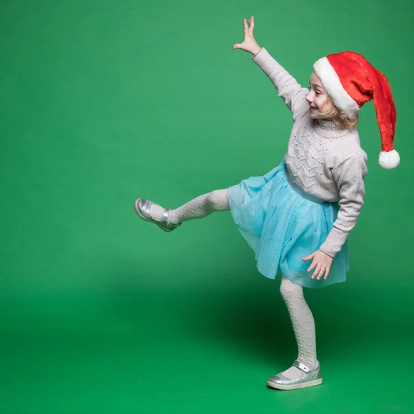 Gelukkig klein meisje in de kerstman hoed springen — Stockfoto