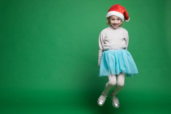 快乐的小女孩戴着圣诞老人的帽子跳着 — 图库照片