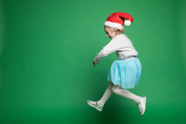 Gelukkig klein meisje in de kerstman hoed springen — Stockfoto