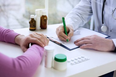 Tıbbi muayene ya da reçete üzerine hasta notları yazan erkek doktor