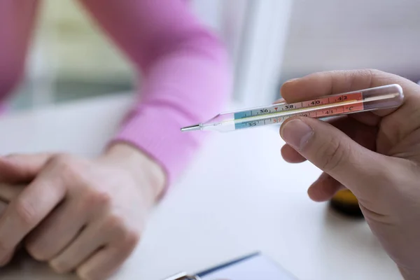 Nahaufnahme einer Frau, die auf das Thermometer blickt. — Stockfoto