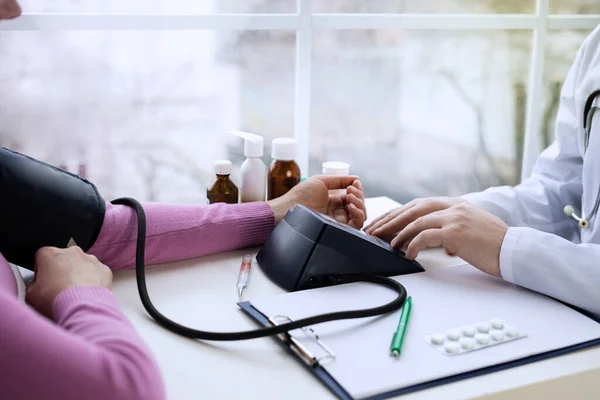 Male doctor measures the pressure with the device to the patient