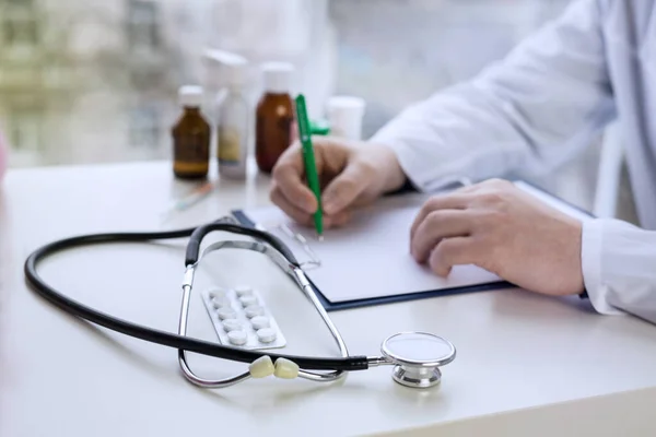 Mężczyzna lekarz piszący notatki pacjenta na temat badania lekarskiego lub recepty — Zdjęcie stockowe