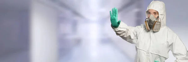 Läkare med helkroppskostym och mask visar stoppskylt med handen. — Stockfoto