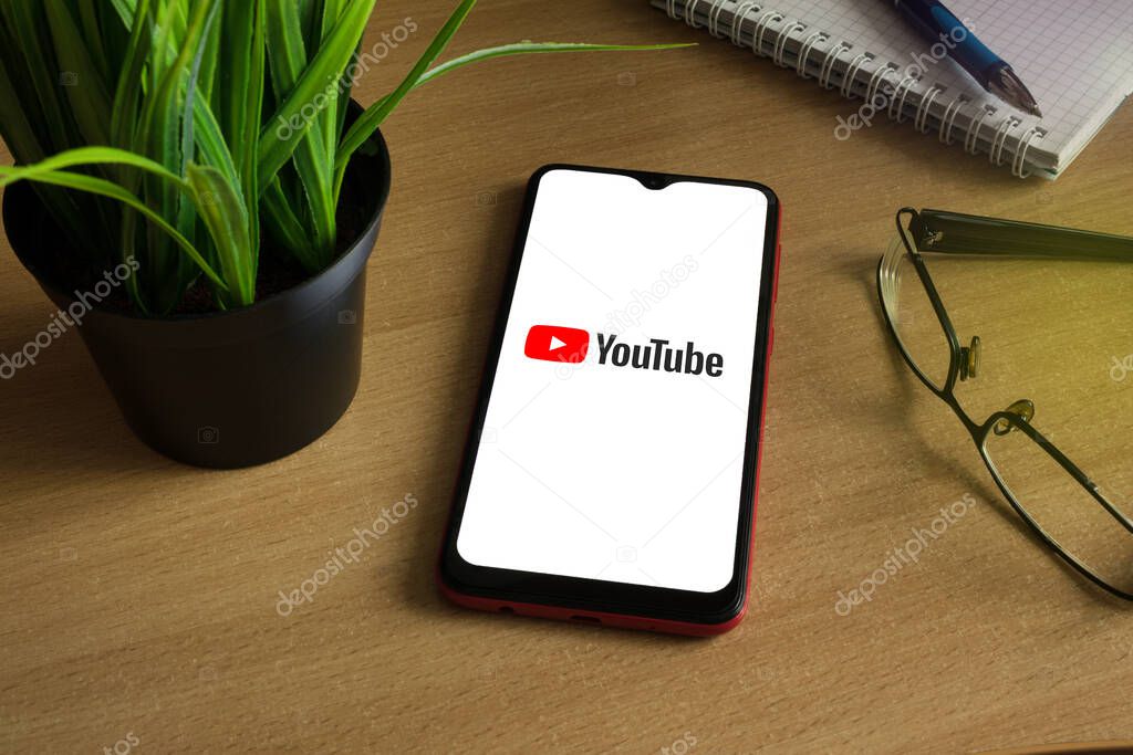 Minsk 12.05.2020. Smartphone on a wooden background with image of logo Youtube.