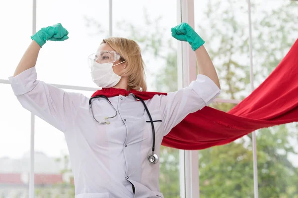 Doutor em terno de super-herói em pé na defesa da pandemia de vírus na janela — Fotografia de Stock