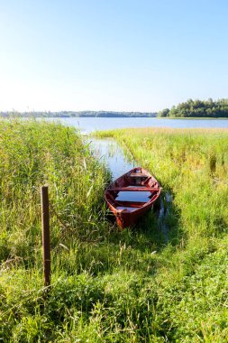Göle yaz güneşte su ile eski kırmızı ahşap balıkçı teknesi