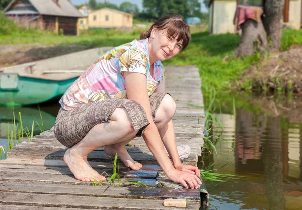 夏天, 年轻女子在湖边的木码头上洗衣服 — 图库照片