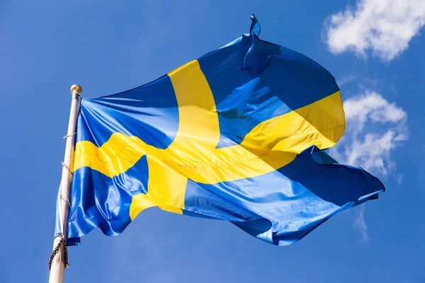Švédská vlajka mávání ve větru na pozadí modré oblohy — Stock fotografie