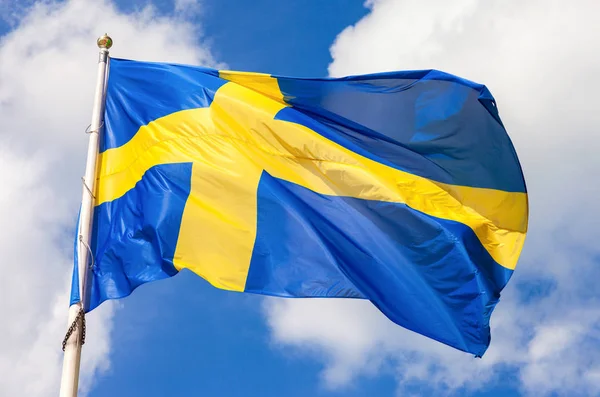 Švédská vlajka modrá se žlutým kříž mávat ve větru proti — Stock fotografie