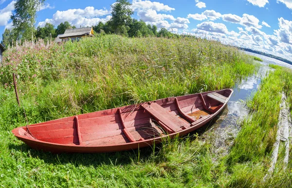 Старая красная деревянная лодка на озере в летний солнечный день — стоковое фото