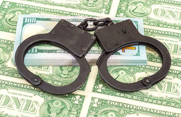 Policji stalowe kajdanki leżącego na stercie dolary amerykańskie — Zdjęcie stockowe