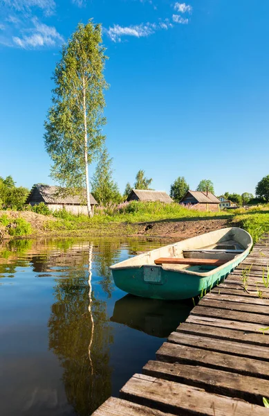 Barco de pesca amarrado en un muelle en el lago por la mañana en summ —  Fotos de Stock