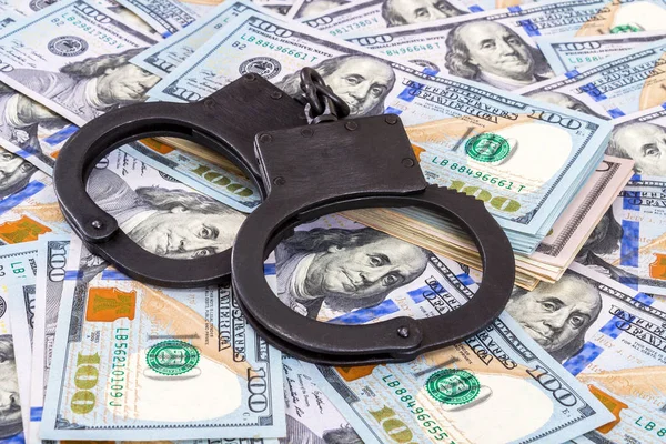 Policji stalowe kajdanki leżącego na stercie dolary amerykańskie — Zdjęcie stockowe