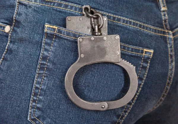 黑色的金属警方手铐在背牛仔裤的口袋里 — 图库照片