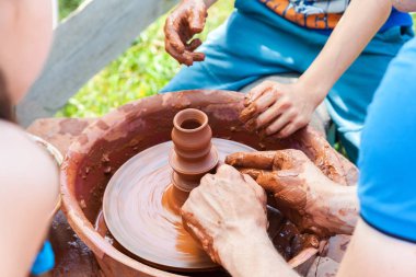 Öğretmen öğrencisinin kırmızı kille çalışmasına yardım ediyor.