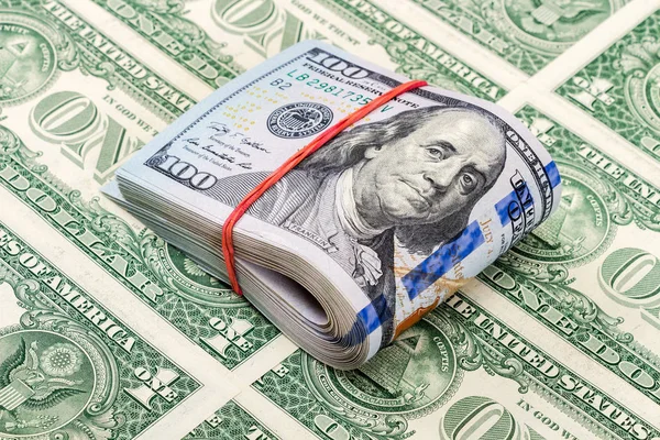 Folded american dollar bills wrapped by rubber band over dollars — Stock Photo, Image