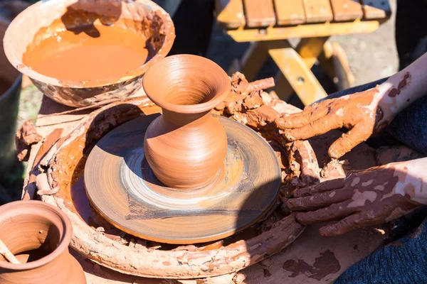 Hands of a potter, creating an ceramic jar on the circle. Work o