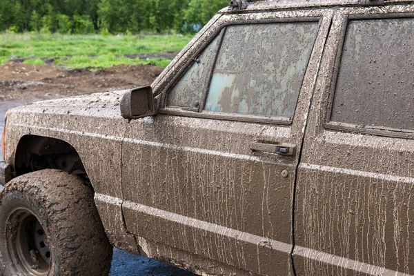 SUV sucio después de conducir en la lluvia en el camino rural extremadamente sucio —  Fotos de Stock