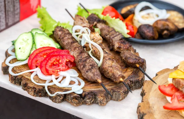 Grilled shish kebab or shashlik on wooden skewers with fresh veg — Stock Photo, Image