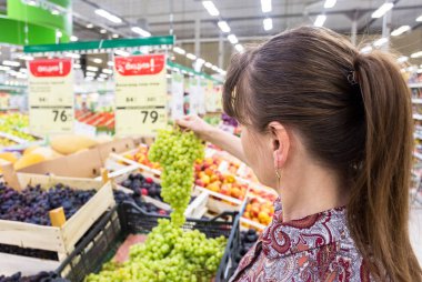 Genç kadın süpermarkette alışveriş, taze üzüm seçimi 