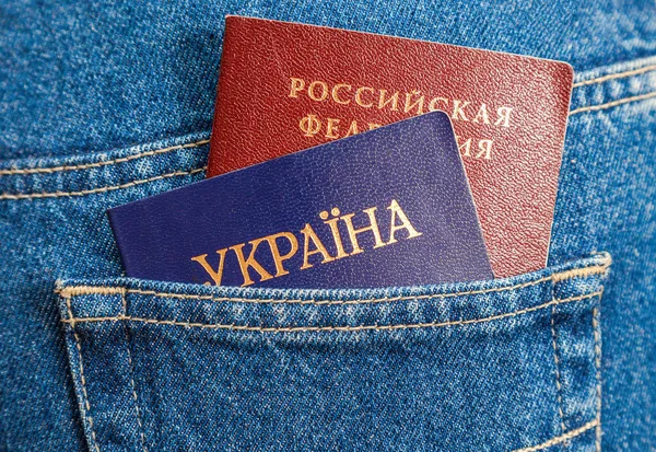 Российские и украинские паспорта в заднем кармане джинсов — стоковое фото