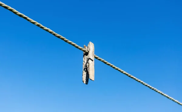 Mavi gökyüzüne karşı halata eski ahşap mandal — Stok fotoğraf