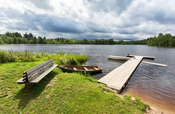 Fiskebåtar förtöjda vid en träbrygga på sjön i sommar sunn — Stockfoto