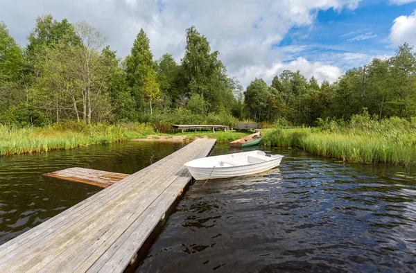 Fishing boats moored at a wooden pier on the lake in summer sunn — Stock Photo, Image