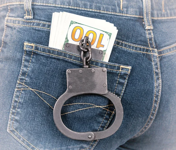 Black metal handcuffs and american currency in back jeans pocket — Stock Photo, Image
