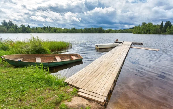 Fiskebåtar förtöjda vid en träbrygga på sjön i sommardag — Stockfoto