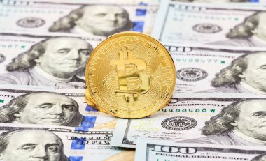 Golden bitcoin on the background of one hundred american dollars clipart