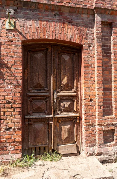 Oude houten deur in het verlaten huis van rode bakstenen — Stockfoto
