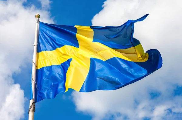 Švédská vlajka se žlutým kříž, mával ve větru proti přikrý — Stock fotografie