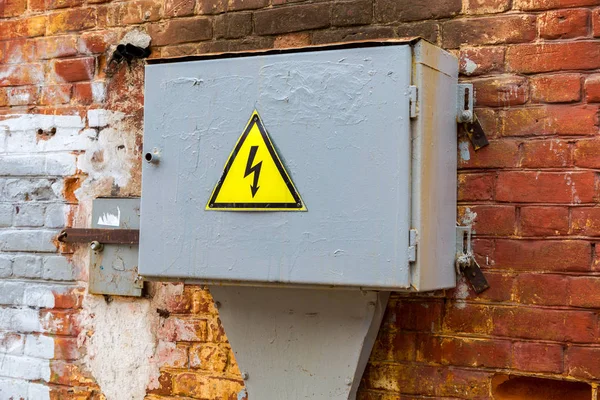 Oude gele hoogspanning waarschuwingsteken opknoping op het vak metall — Stockfoto